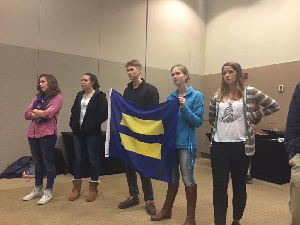 Students protest during Counter Culture speaker event by holding up a Human Rights Campaign flag, facing the speaker.