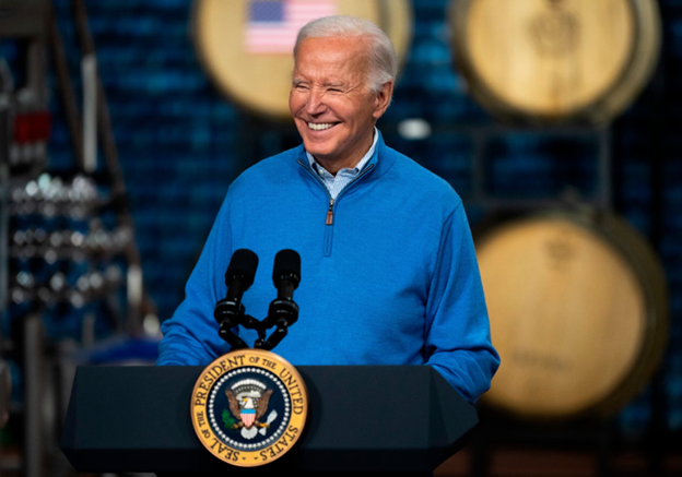 Biden stands at the presidential podium smiling.
